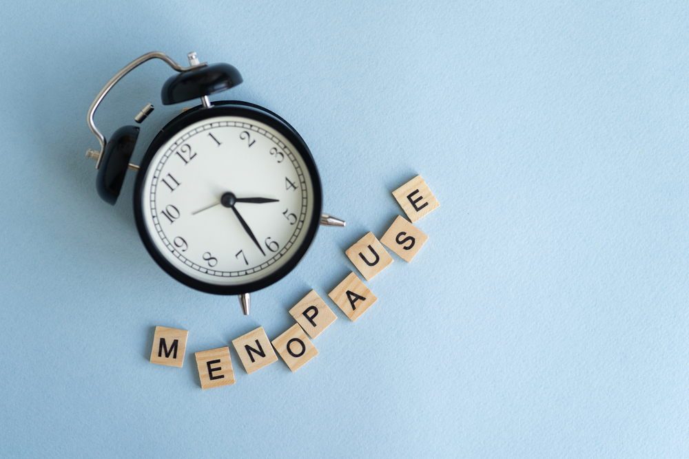 Menopause alphabets wooken blocks under a clock pointing 4;30 denoting the menopause age