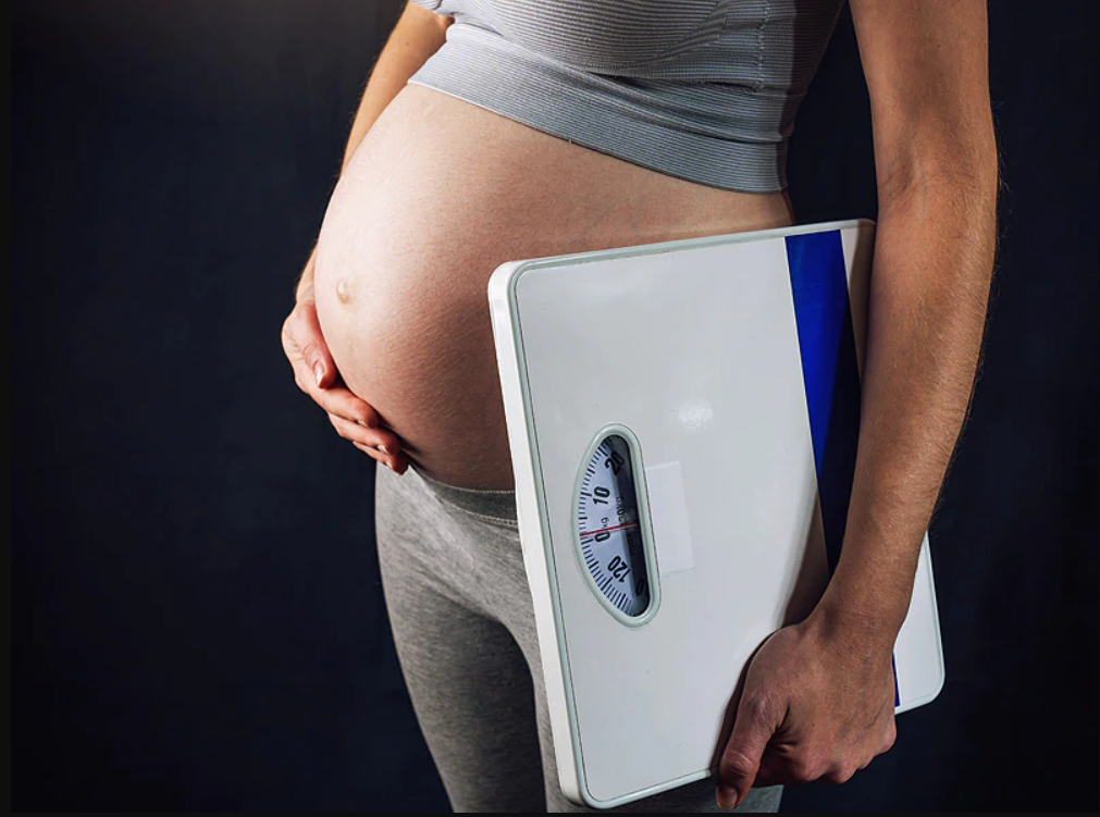 Pregnant woman with weighing machine in hand